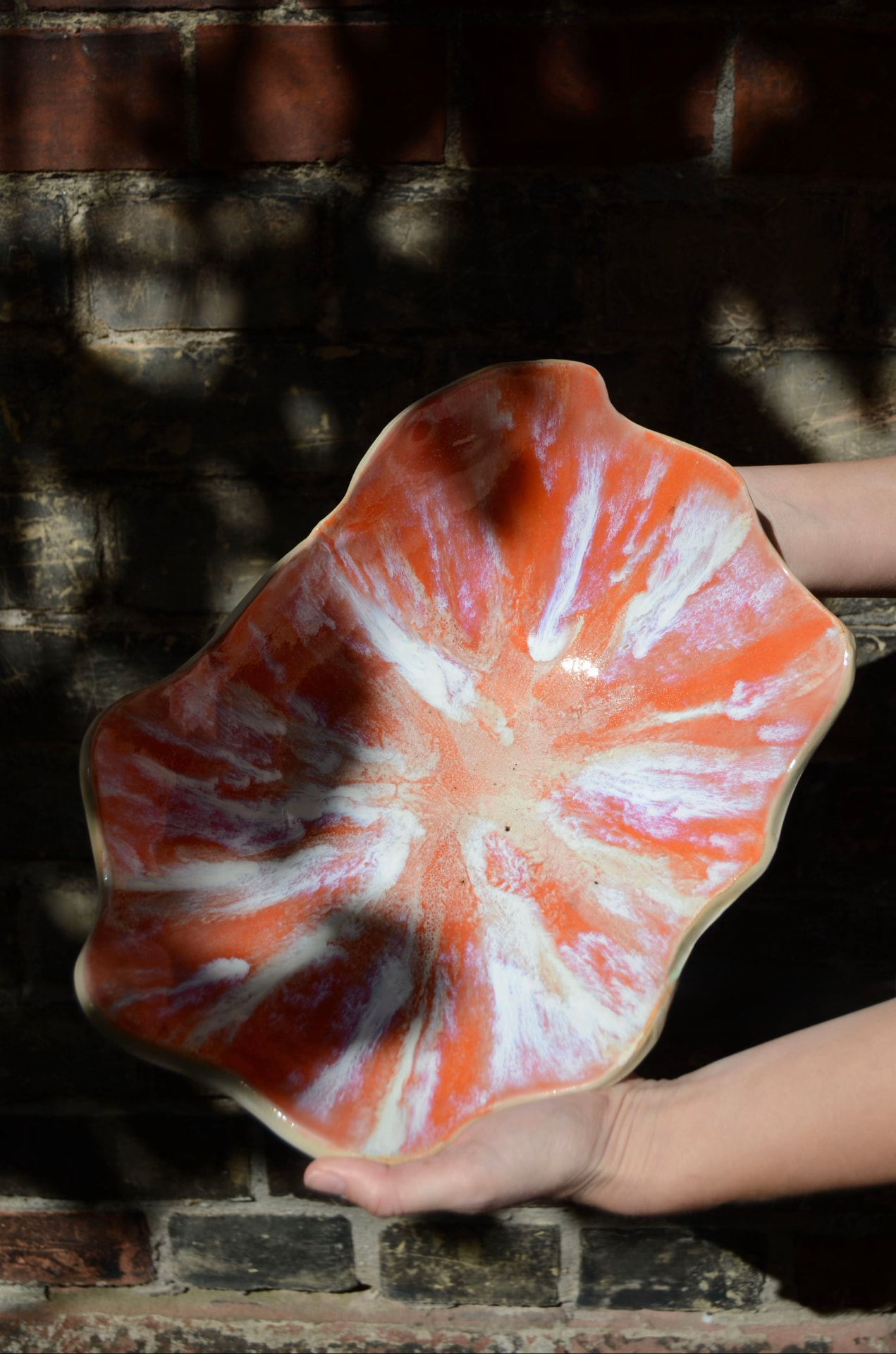 Finished coral glazed belly bowl held in two hands